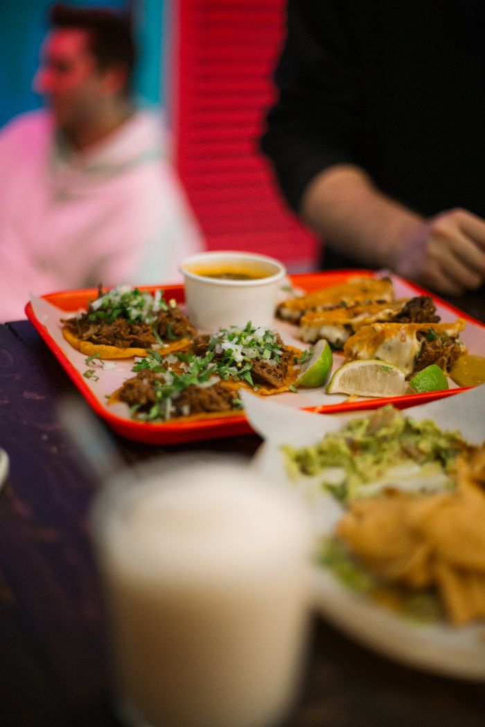 Tacos served with lime and dip on a vibrant red tray, creating a warm and inviting atmosphere.