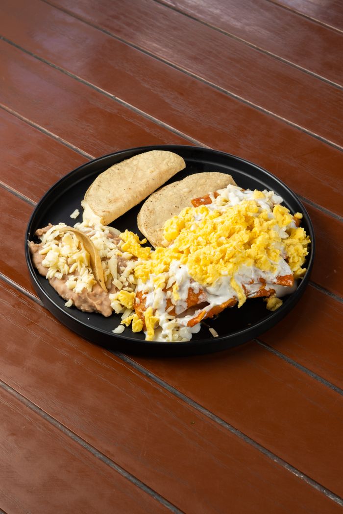 Delicious Mexican breakfast featuring scrambled eggs, beans, and tortillas served on a rustic wooden table.