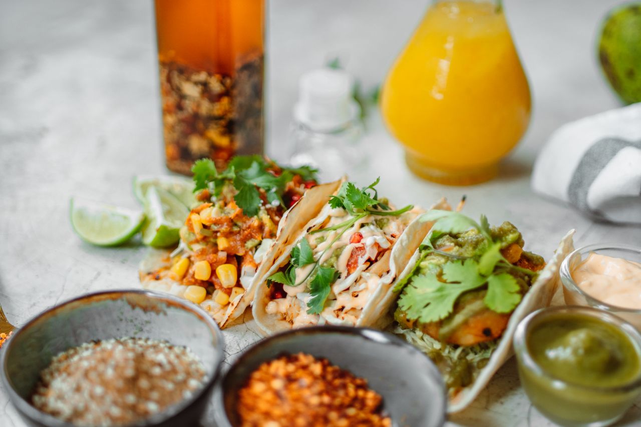 Delicious Mexican tacos paired with assorted spices and refreshing juice, perfect for food enthusiasts.